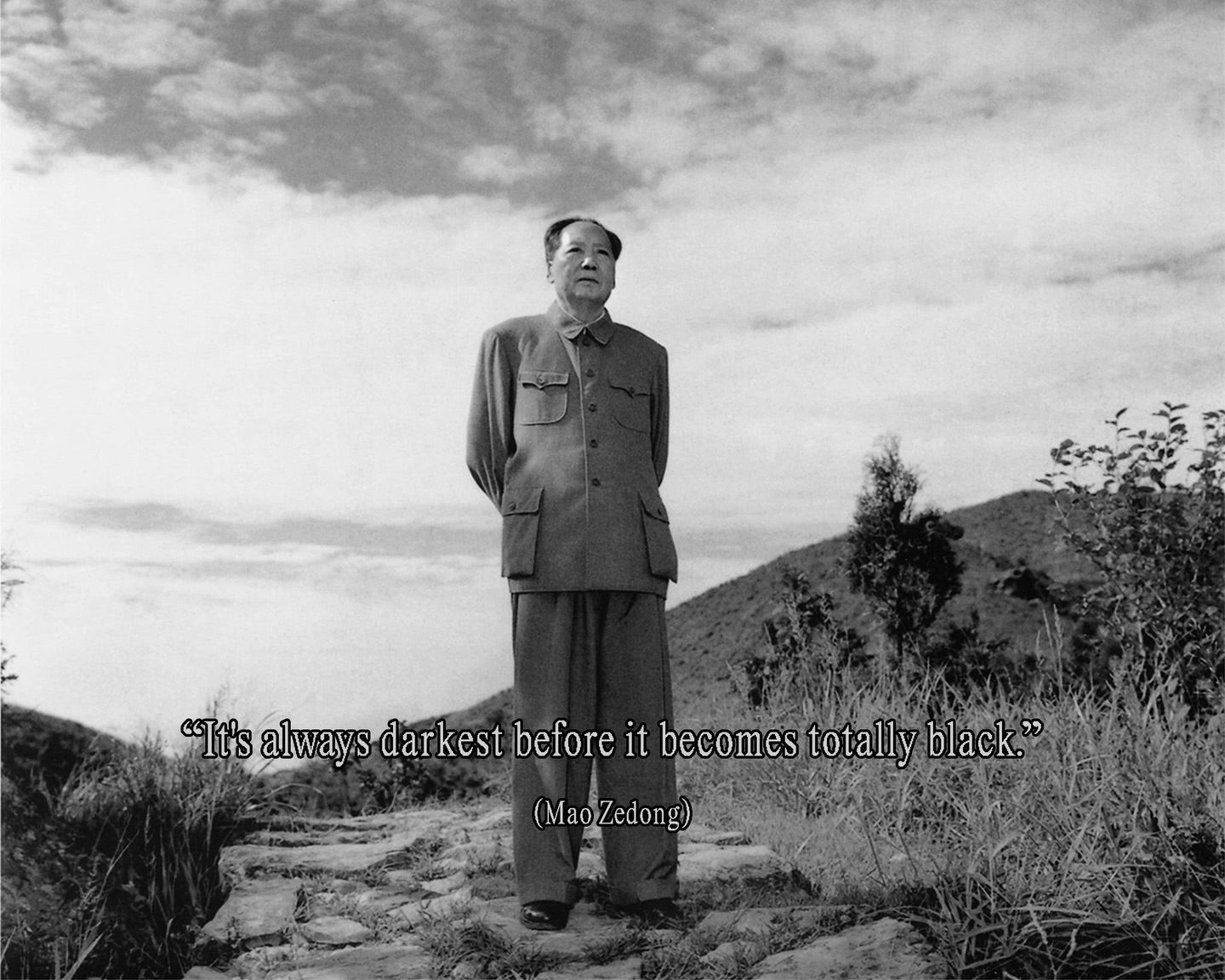 Black-and-white photo of Mao Zedong standing on a hillside path in a gray Zhongshan suit, gazing upward, with the caption 